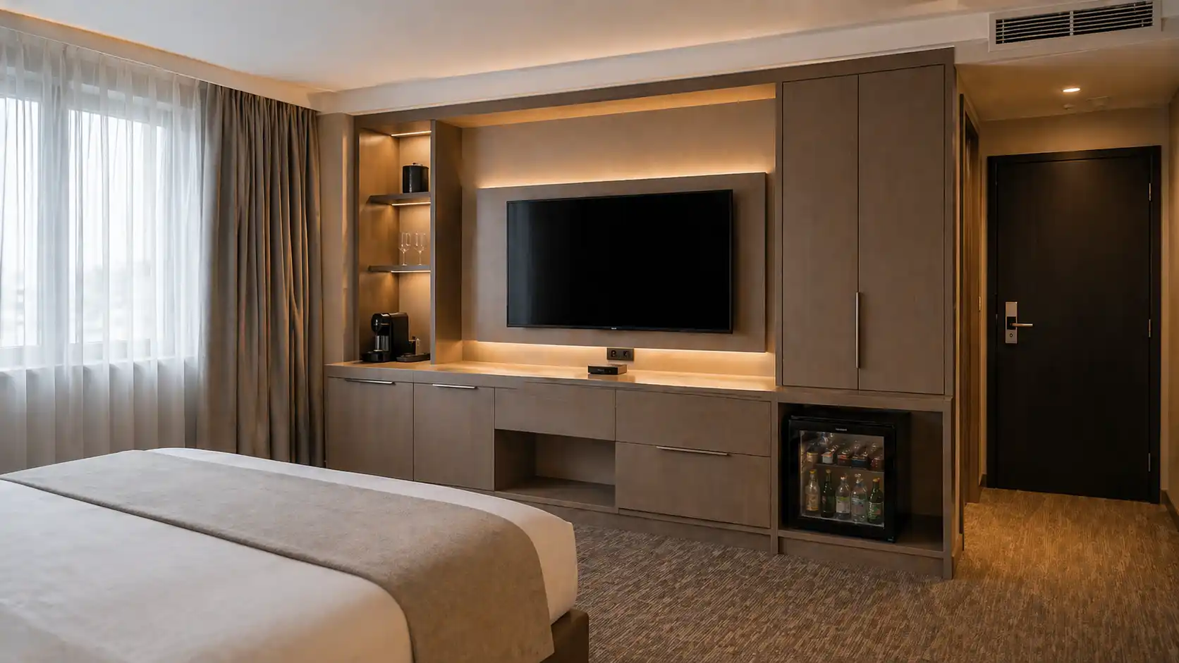 Zabudowana ściana TV w pokoju hotelowym z półkami, szafkami i minibarem