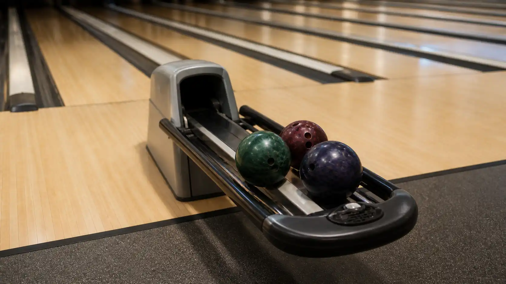 Standardowy ball return z kulami bowlingowymi przy stanowisku gracza