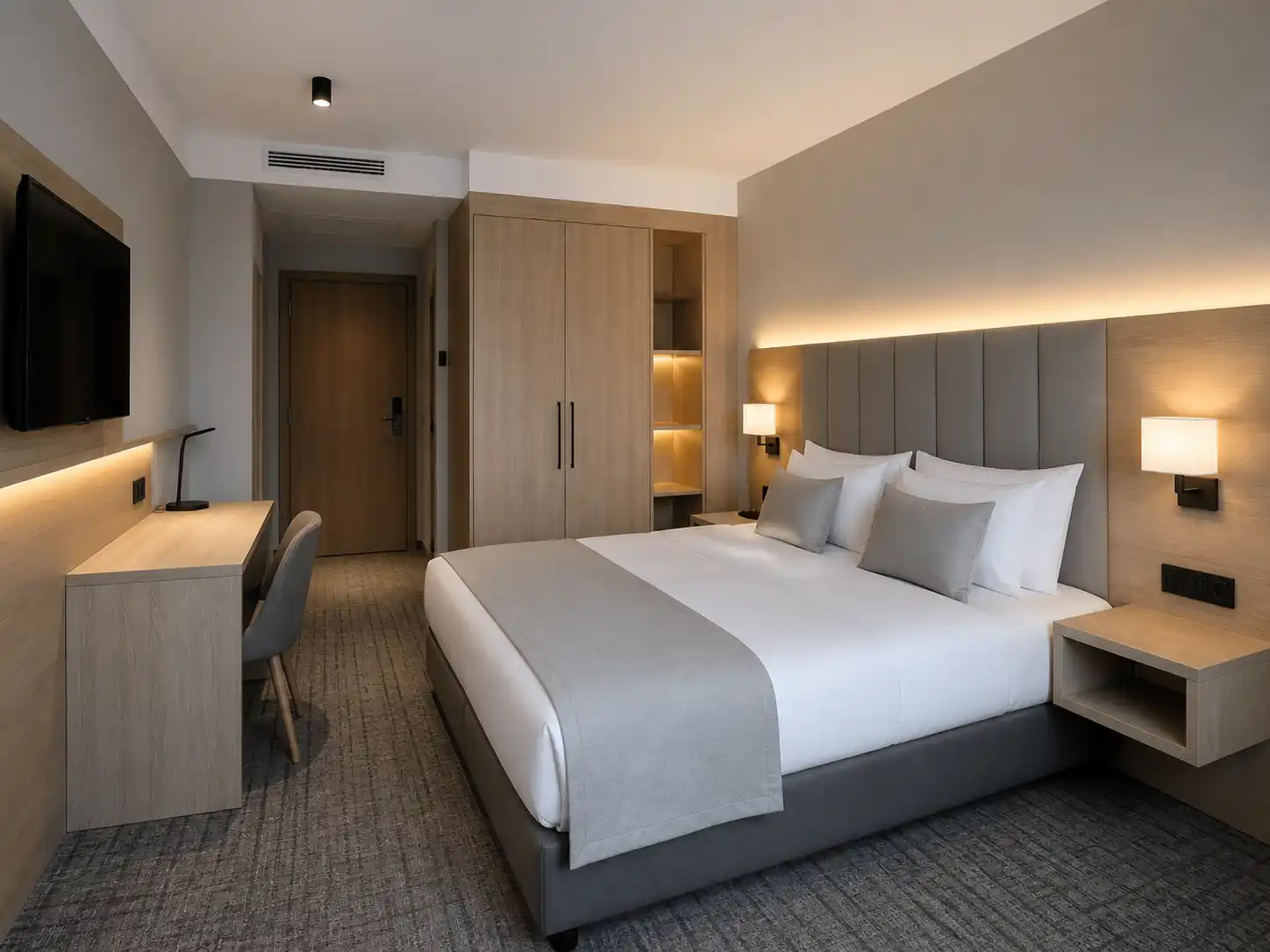 Nowoczesny pokój hotelowy z prostą zabudową, jasnym drewnem i neutralną kolorystyką