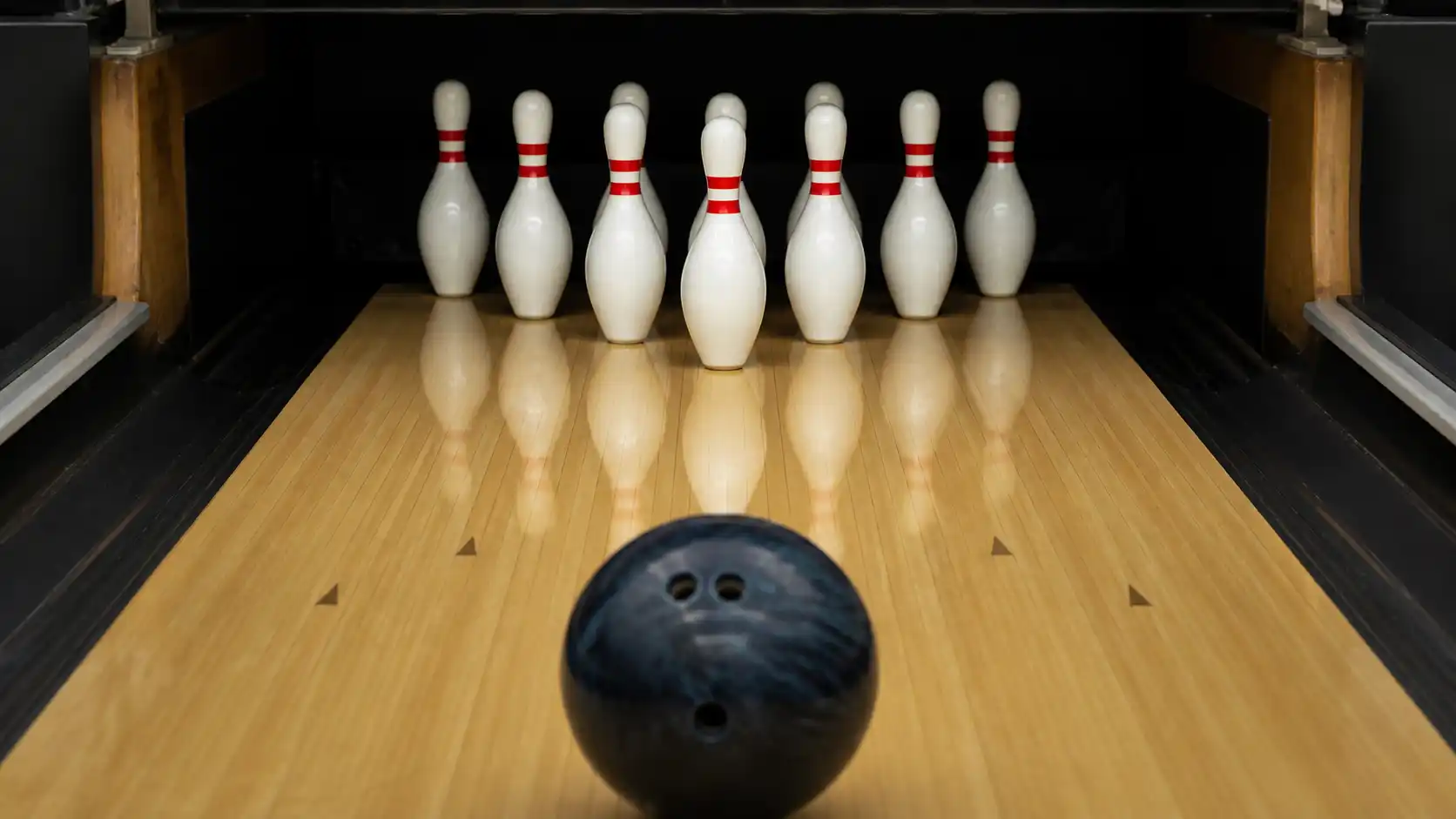 Bowling 10-pin z dziesięcioma kręglami ustawionymi w trójkąt i kulą z otworami