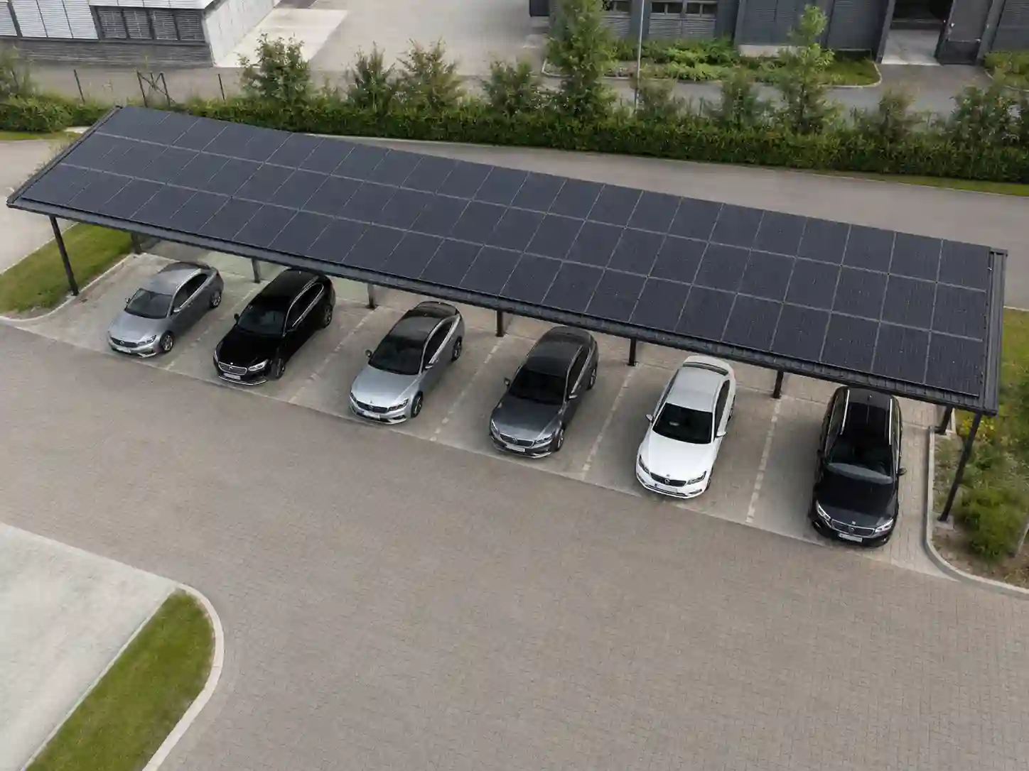 Jednostronna wiata fotowoltaiczna nad jednym długim rzędem samochodów.