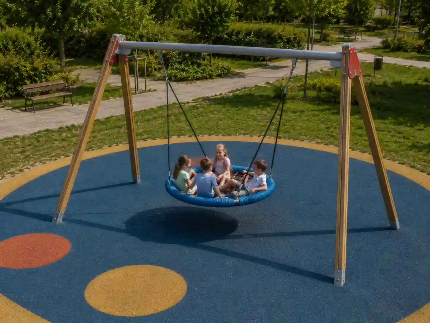 Publiczna huśtawka typu bocianie gniazdo użytkowana przez kilkoro dzieci.