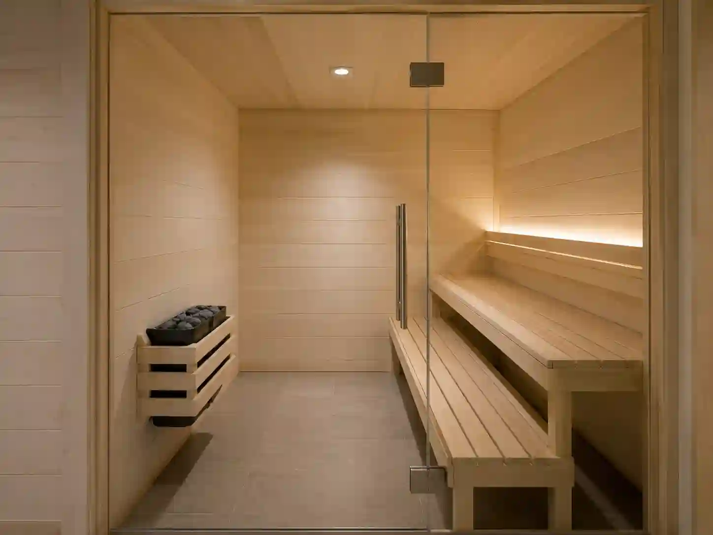 Mała sauna fińska z kompaktowym piecem elektrycznym zawieszonym na ścianie.