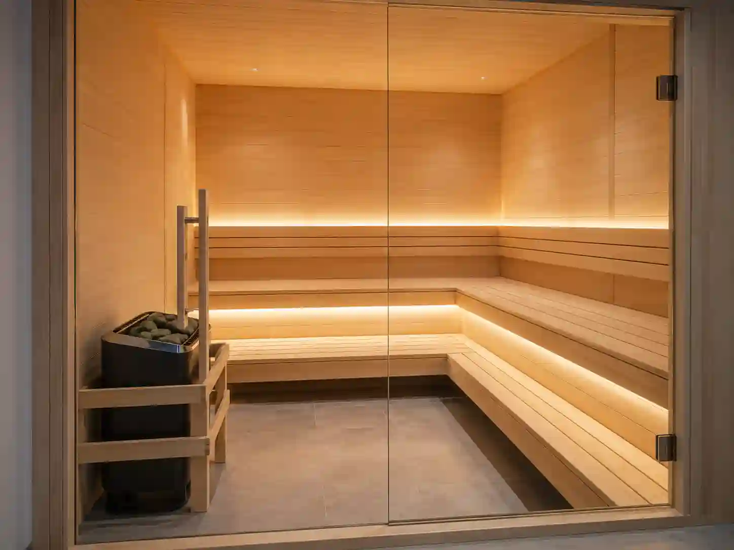 Sauna fińska z piecem elektrycznym ustawionym przy szklanych drzwiach wejściowych.