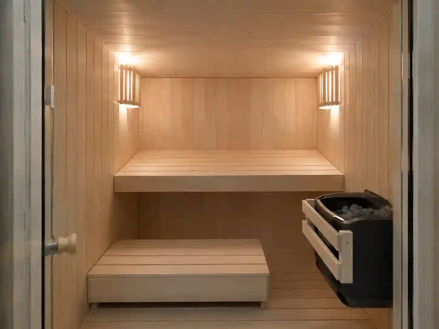 Niska i kompaktowa sauna fińska z jedną główną ławką w małym pomieszczeniu.