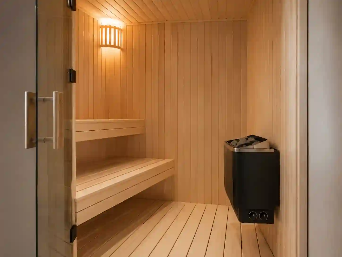 Mała sauna fińska z mechanicznymi pokrętłami sterującymi umieszczonymi na obudowie pieca.