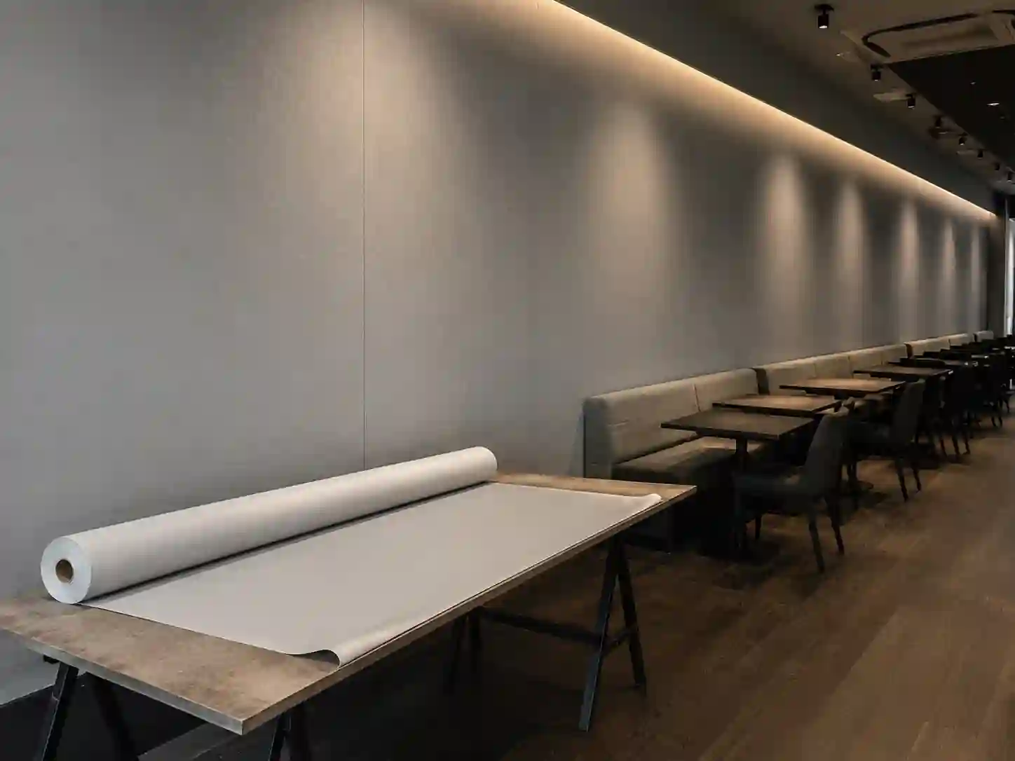 Szeroka tapeta obiektowa montowana na długiej prostej ścianie restauracji.