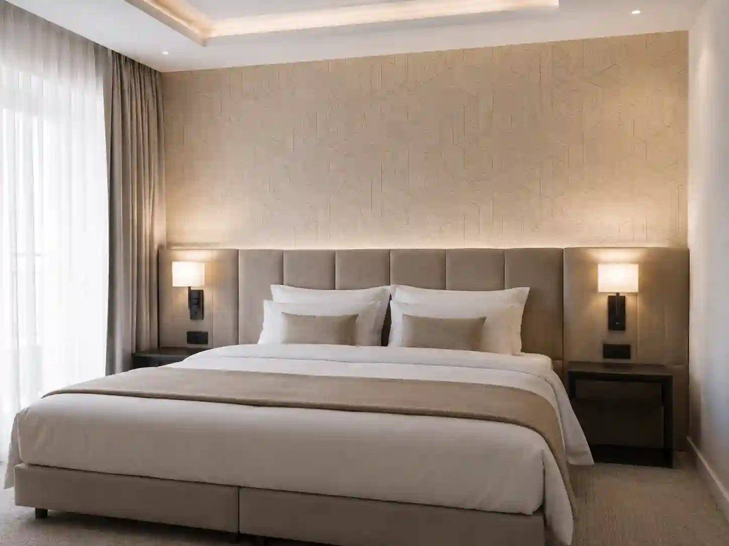 Tapeta obiektowa o delikatnej strukturze na ścianie za łóżkiem w pokoju hotelowym.