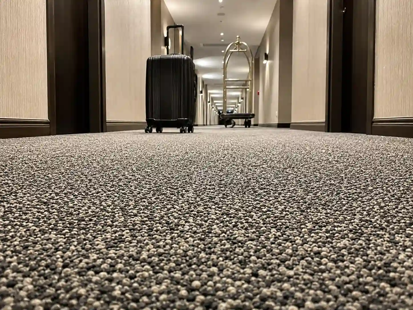 Niska wykładzina hotelowa ułatwiająca przejazd walizek i wózków w korytarzu.
