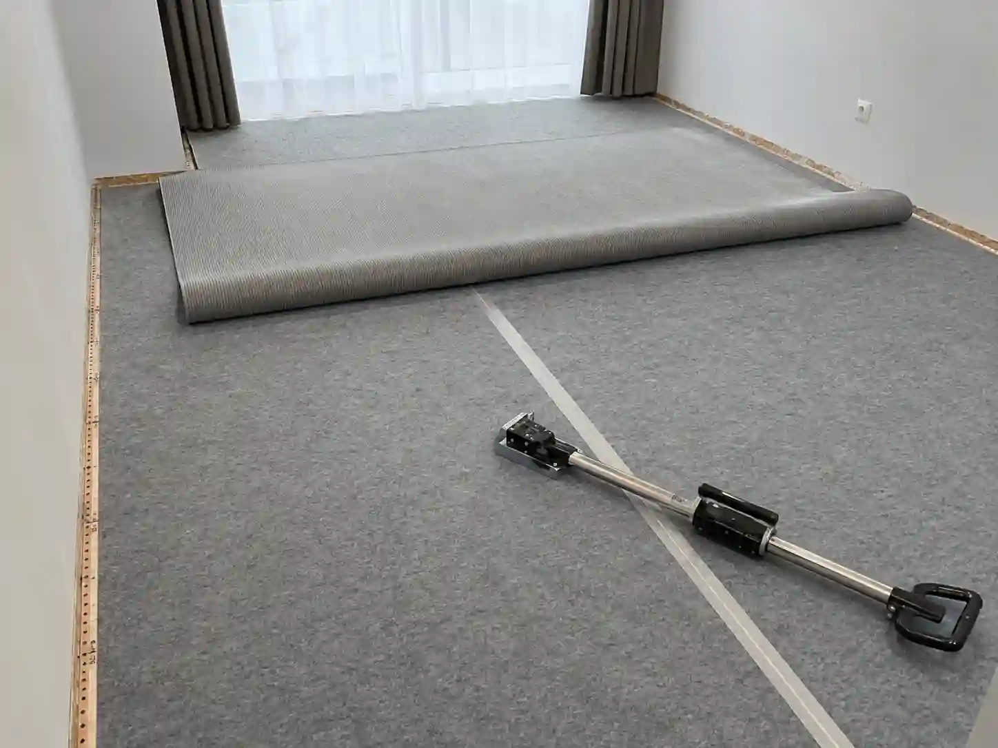 Montaż napinanej wykładziny na miękkim podkładzie w pokoju hotelowym.
